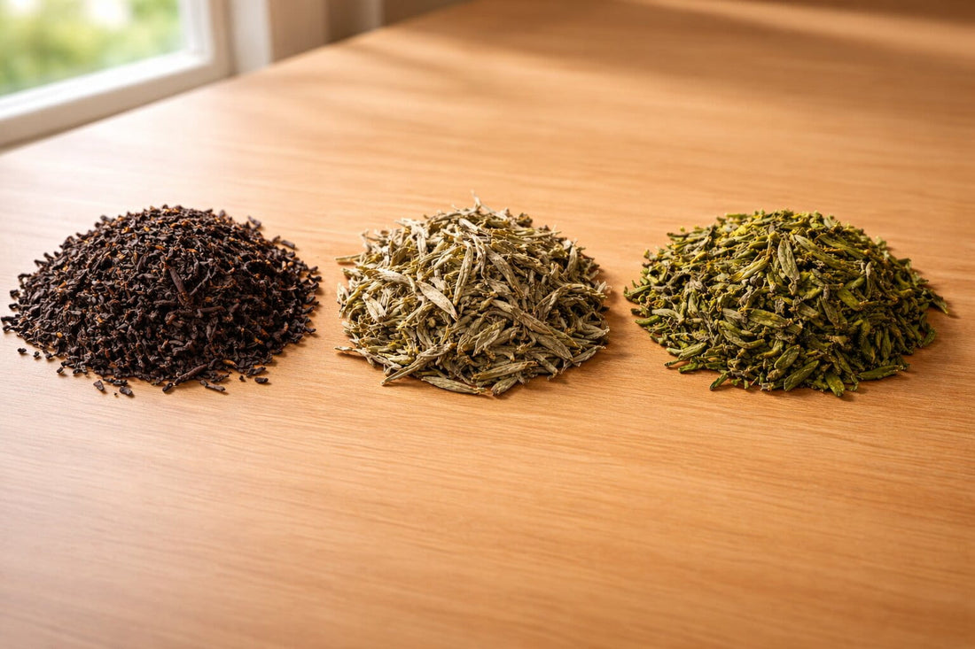 Assortment of loose leaf teas including green, black, oolong, and white tea displayed in ceramic bowls on a natural wooden surface with soft daylight.