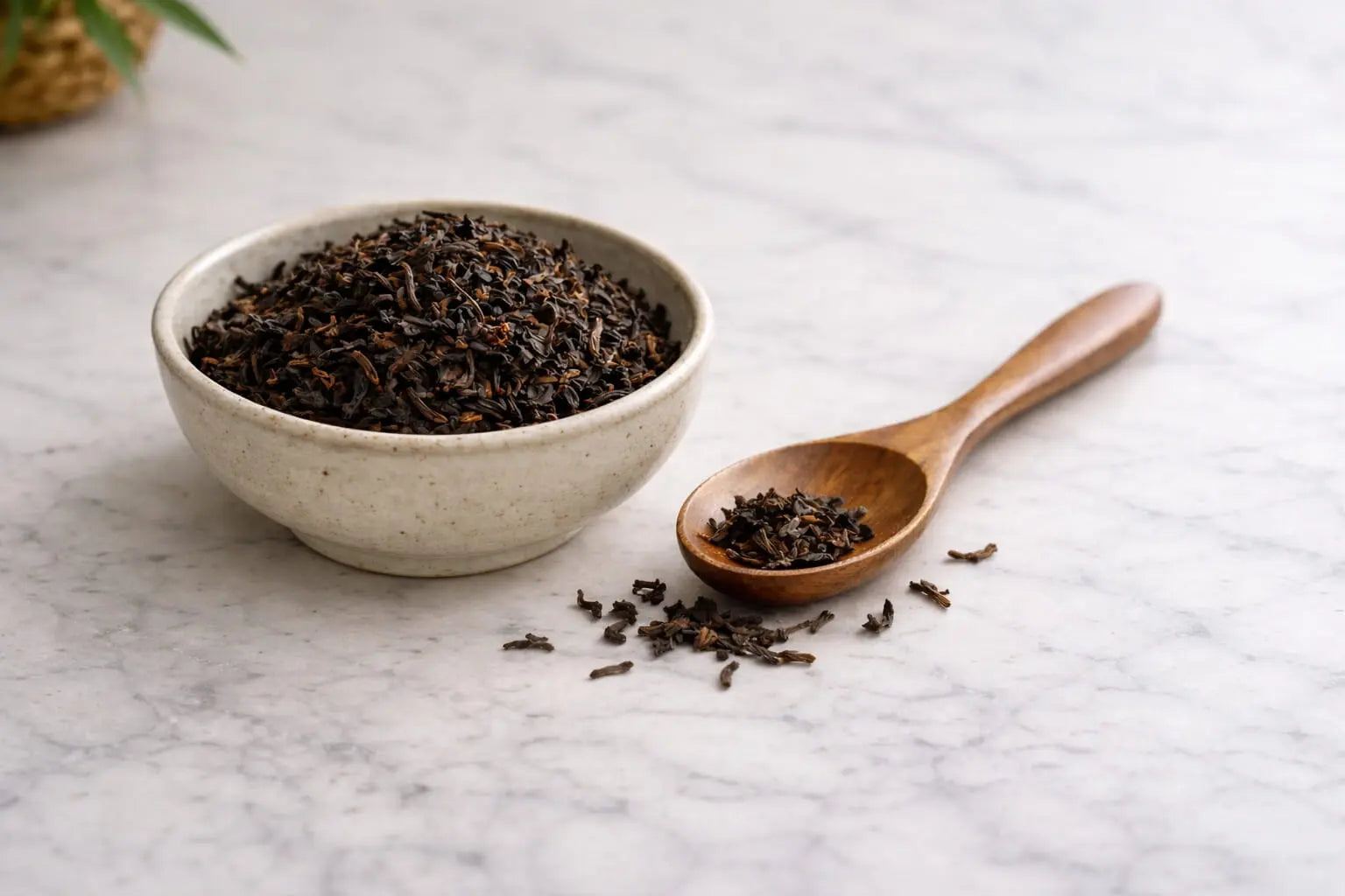 Loose leaf black tea in a ceramic bowl on a marble table